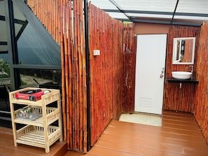 Un baño con pared de madera, una puerta blanca y un lavamanos con espejo.