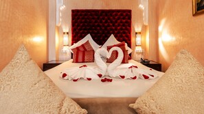 A hotel room with a bed, red and white pillows, a red headboard, and a decorative swan made of towels. - Riad Sultan Suleiman & SPA (Marrakech)