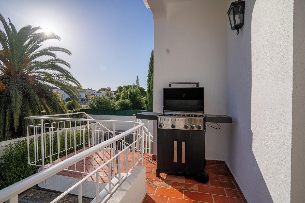 Un espace barbecue extérieur avec un mur blanc et une rambarde en métal.