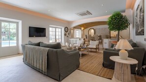 Ein modernes Wohnzimmer mit einer Couch, Sesseln, einem Couchtisch und einem Essbereich mit Stühlen.