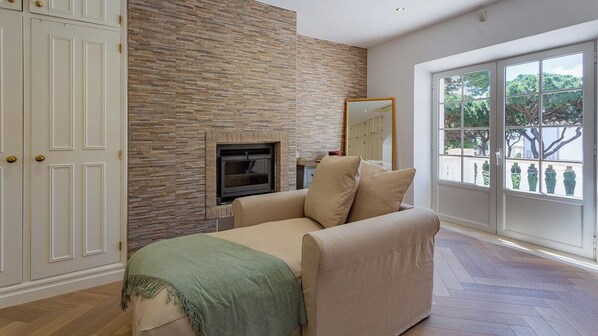 A room with a fireplace, a sofa, a large window with a view, and a door with a mirror. - Portuguese mansion close to marina, golf and beach (Quarteira)