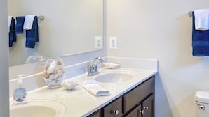 Une salle de bain avec deux lavabos, un miroir et des toilettes.