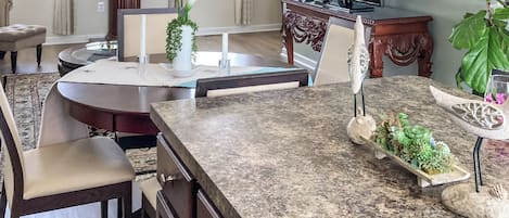 A modern kitchen with a granite countertop, wooden cabinets, and a dining area with a table and chairs.