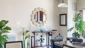 Un coin repas avec une table ronde, des chaises, un miroir décoratif et des plantes en pot.