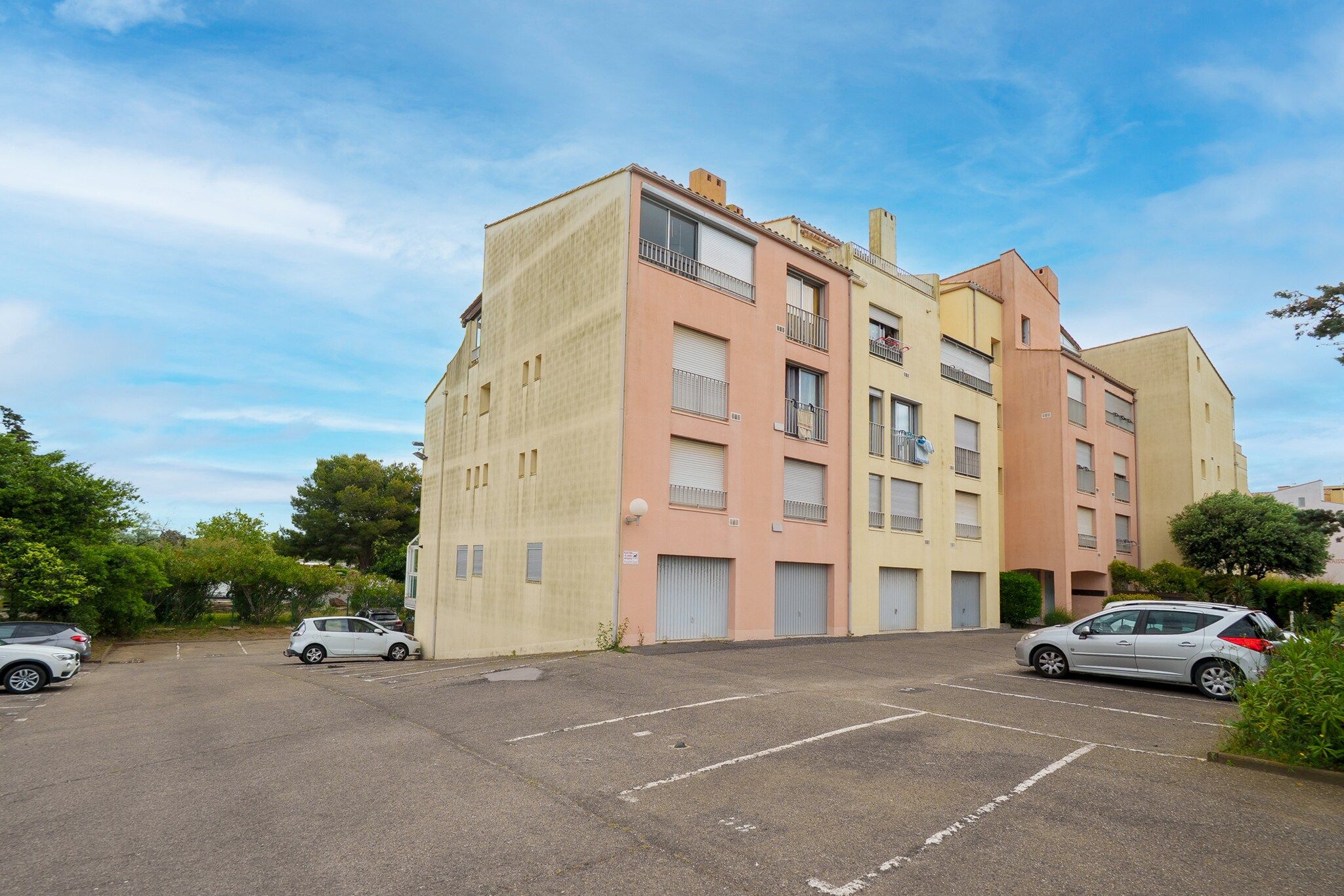 A multi-story residential building with a parking lot in front.