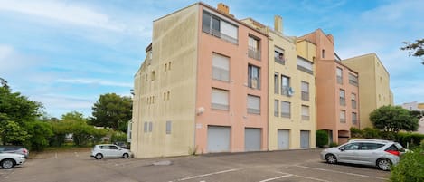 A multi-story residential building with a parking lot in front.