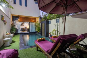 A pool area with lounge chairs and a pergola.