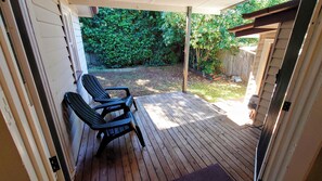 A covered patio with wooden flooring and two chairs.
