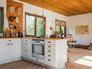 Eine Küche mit Holzausstattung, einem eingebauten Backofen und einem Fenster mit Blick auf Grünflächen.