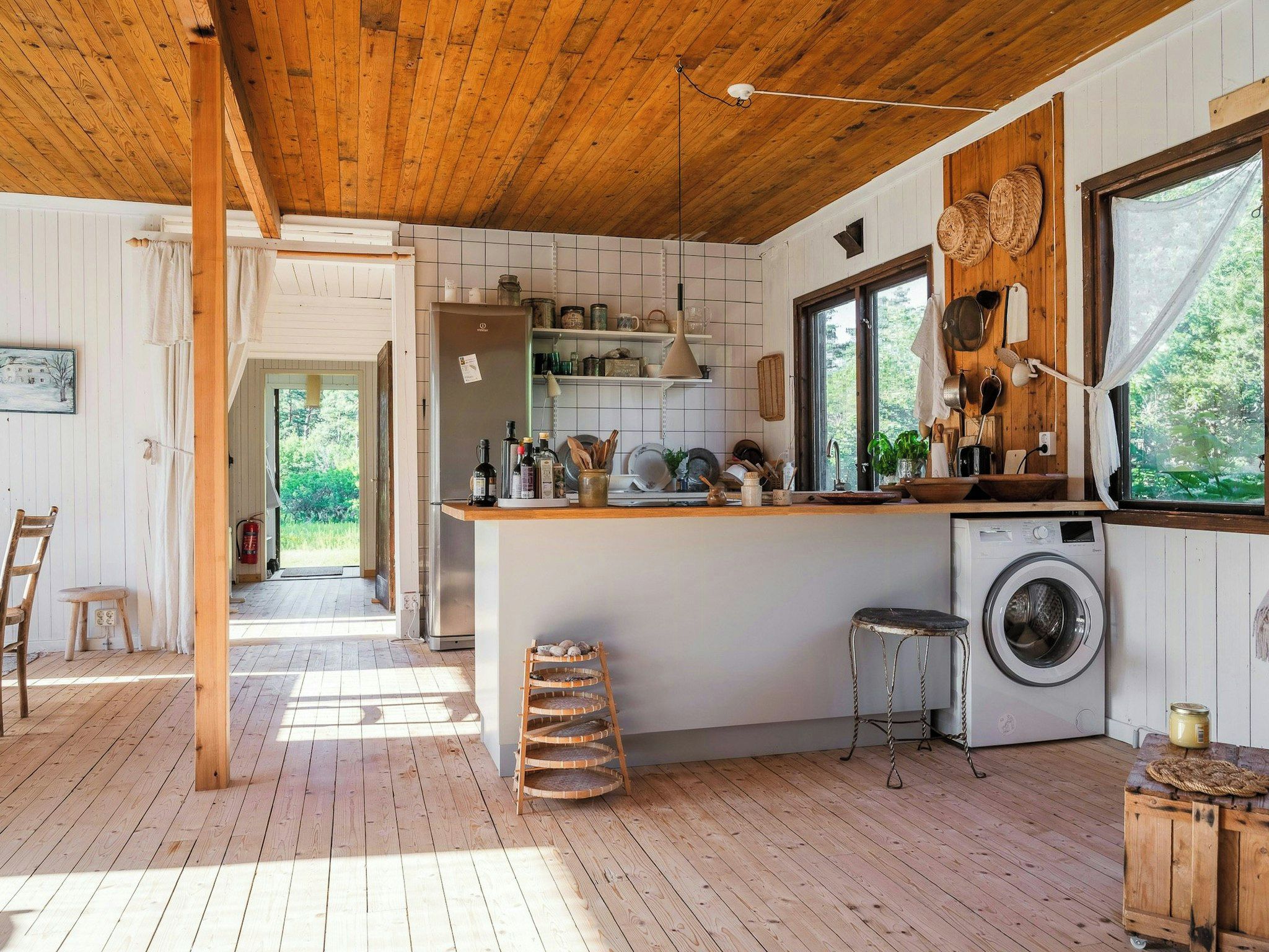 Een landelijke keuken met houten balken, een wasmachine en een groot raam.