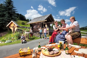Eine Holzhütte mit geneigtem Dach, eingebettet in eine üppige grüne Landschaft unter blauem Himmel.