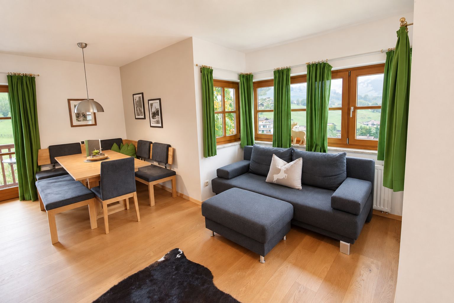 A modern living room with a dining area, green curtains, and a view of the outdoors.