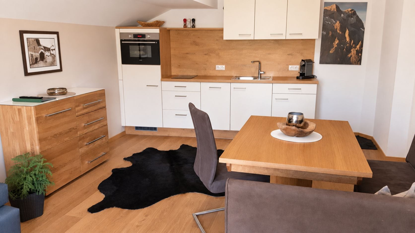 Eine kompakte Küche mit weißen Schränken, einem schwarzen Backofen und einer Holz Arbeitsplatte.