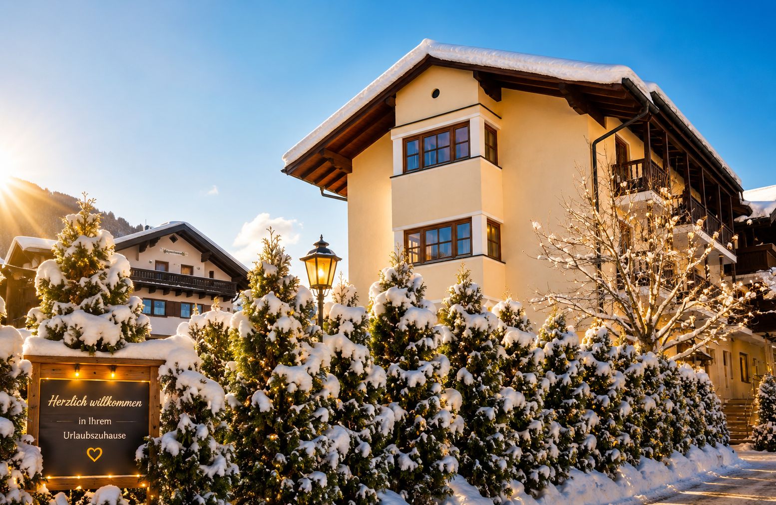 Un hotel con l'ingresso imbiancato dalla neve, un cartello di benvenuto e montagne sullo sfondo.