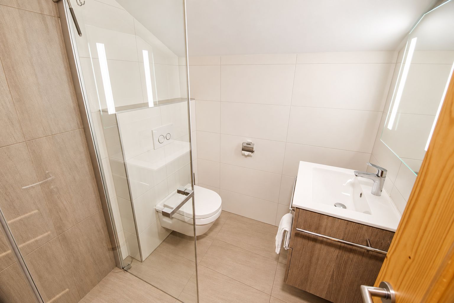 Ein modernes Badezimmer mit einer Duschkabine aus Glas, einer weißen Toilette und einem Holzlagerfläschchen mit Spiegel.