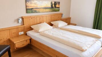 Ein Doppelbett mit Holz Kopfteil und Nachttischen, ein Gemälde darüber und ein grüner Vorhang zur Rechten.