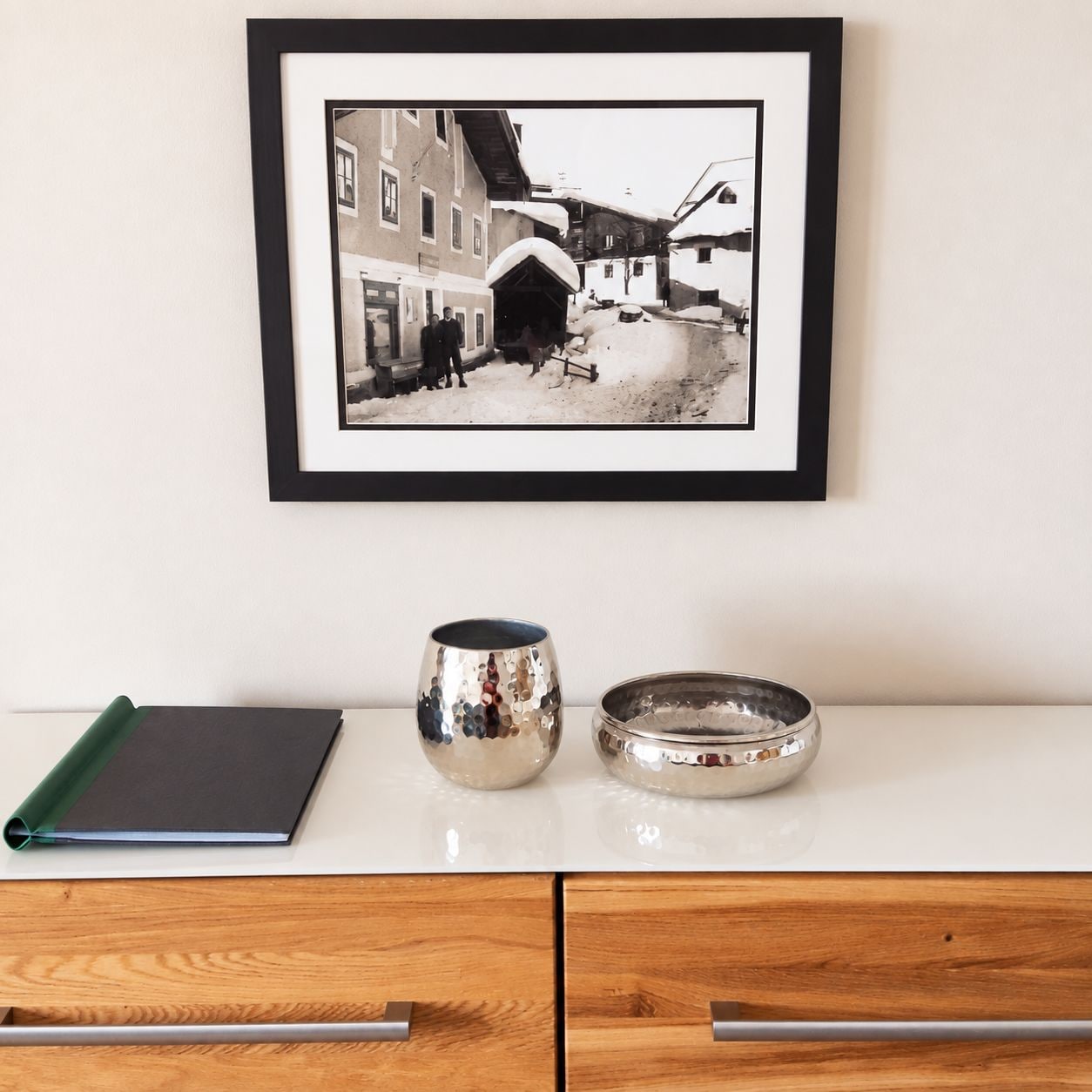 A framed black and white photograph of a street scene with buildings and a snow-covered ground.
