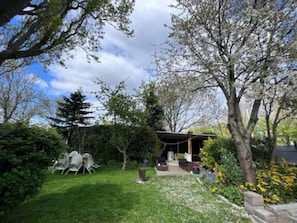 A garden with a patio area, outdoor seating, and a variety of plants.