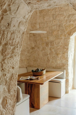 A stone-walled interior with a wooden table and white cushioned seating. - Trulli between Tradition and Comfort with Pool (Ostuni)