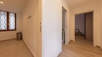 A hallway with a window, a door, and a trash bin.