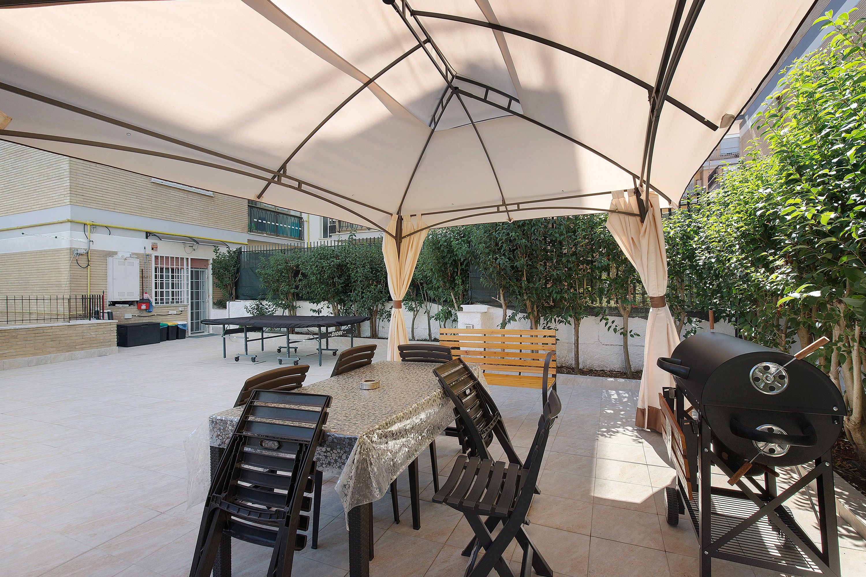 An outdoor patio with a covered dining area, a grill, and a table set for four.