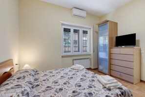 Ein Schlafzimmer mit einem Bett, einem Fernseher, einem Kleiderschrank und einem Fenster.
