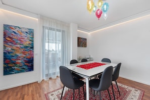 A modern dining room with a white table, black chairs, a red runner, and a colorful abstract painting. - Apartment 'Casa della Luna' (Lecce)