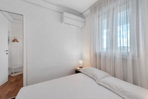 A hotel room with a bed, a nightstand with a lamp, a wardrobe, and a window with sheer curtains. - Apartment 'Casa della Luna' (Lecce)