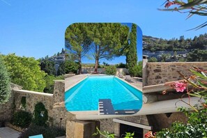A swimming pool with a stone wall and a view of trees and hills. - Mas de L" Embeli with Pool (Mouries)