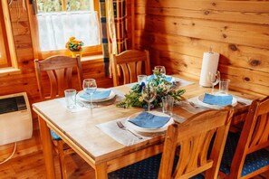 A wooden dining table set for four with blue napkins, glasses, and a candle. - The Fox's Den - Log Cabin 3 (Bad Sachsa \/ OT Steina)