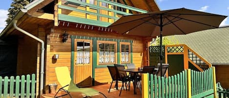 Eine Holzhütte mit einer Terrasse, Sitzgelegenheiten im Freien und einer überdachten Veranda.