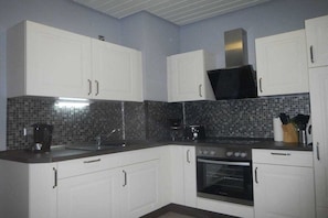 A kitchen with white cabinets, a microwave, a coffee maker, and a tiled backsplash. - The Fox's Den - SweetDreams (Bad Sachsa)