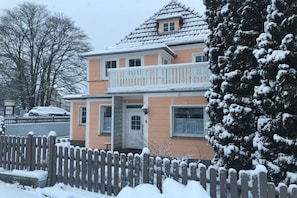 A two-story house with a balcony, a picket fence, and snow-covered trees. - The Fox's Den - SweetDreams (Bad Sachsa)