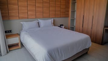 Ein ordentlich bezogenes Bett mit weißen Leinen in einem modernen Zimmer mit Holzvertäfelung an den Wänden und einem Holzschrank.