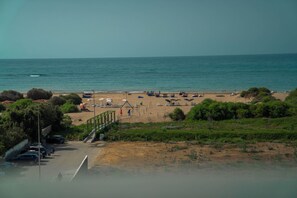 A beach with boats, umbrellas, and a parking area.