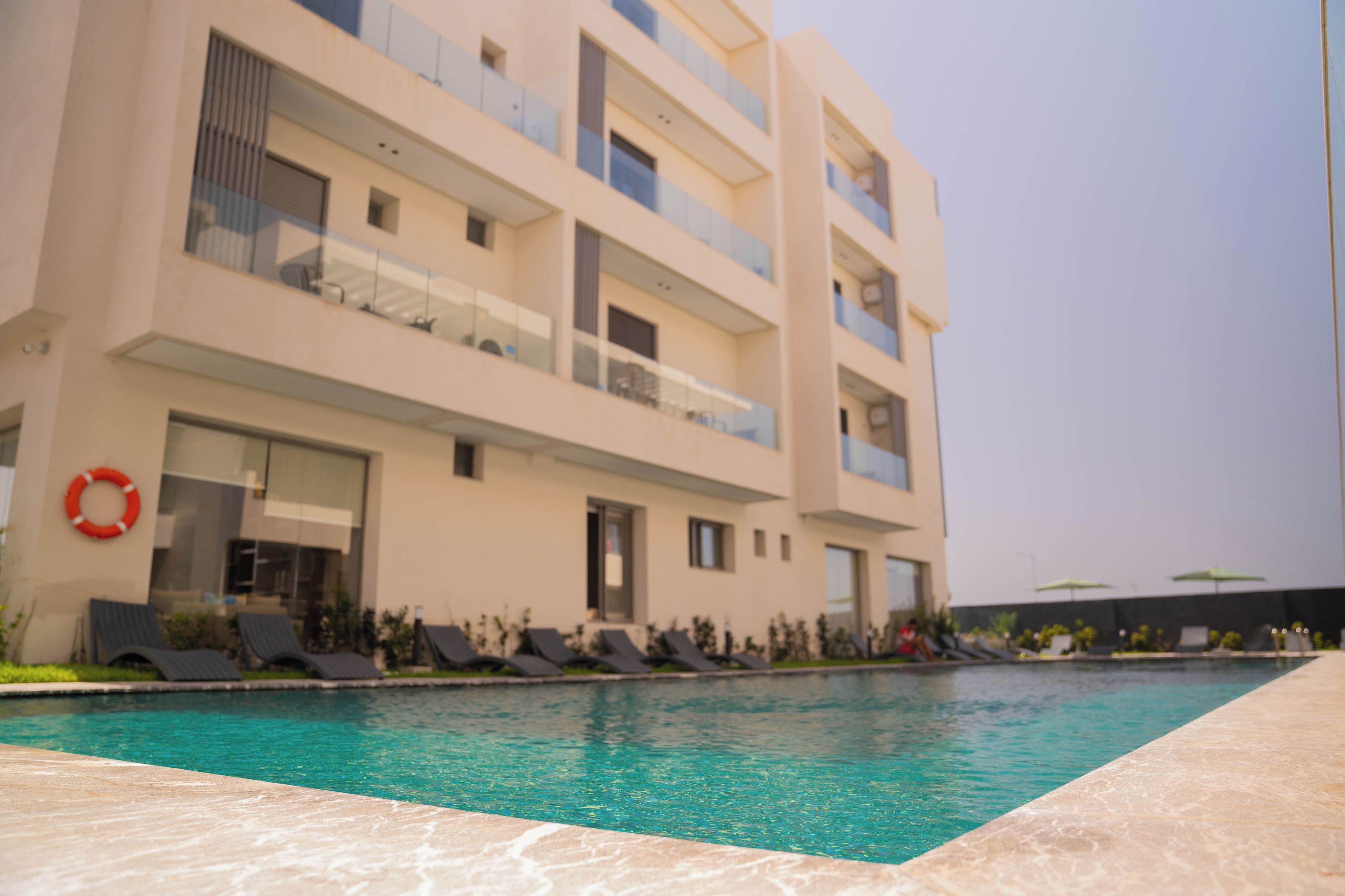 Un edificio moderno con piscina, varios balcones y un flotador.