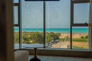 A room with a large window overlooking a beach.