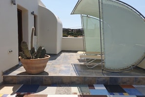A patio area with a large potted cactus, a sunshade, and a chair. - Villa in Pitsidia with swimming pool (Pitsidia)