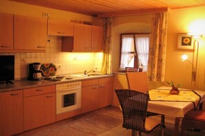 Une cuisine avec des meubles de rangement en bois, une cuisinière, un évier et un coin repas comprenant une table et une chaise.