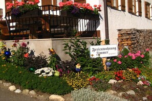 L’entrée d’un hôtel, avec un panneau indicateur, des parterres de fleurs et un escalier.