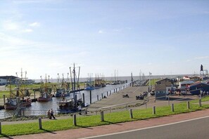 A harbor with boats docked, a pedestrian path, and a small building. - Holiday home with 1 bedroom (Wurster Nordseeküste)