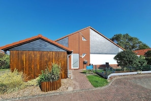 A building with a brick facade, a sloped roof, and a small adjacent wooden structure. - Holiday home with 1 bedroom (Wurster Nordseeküste)