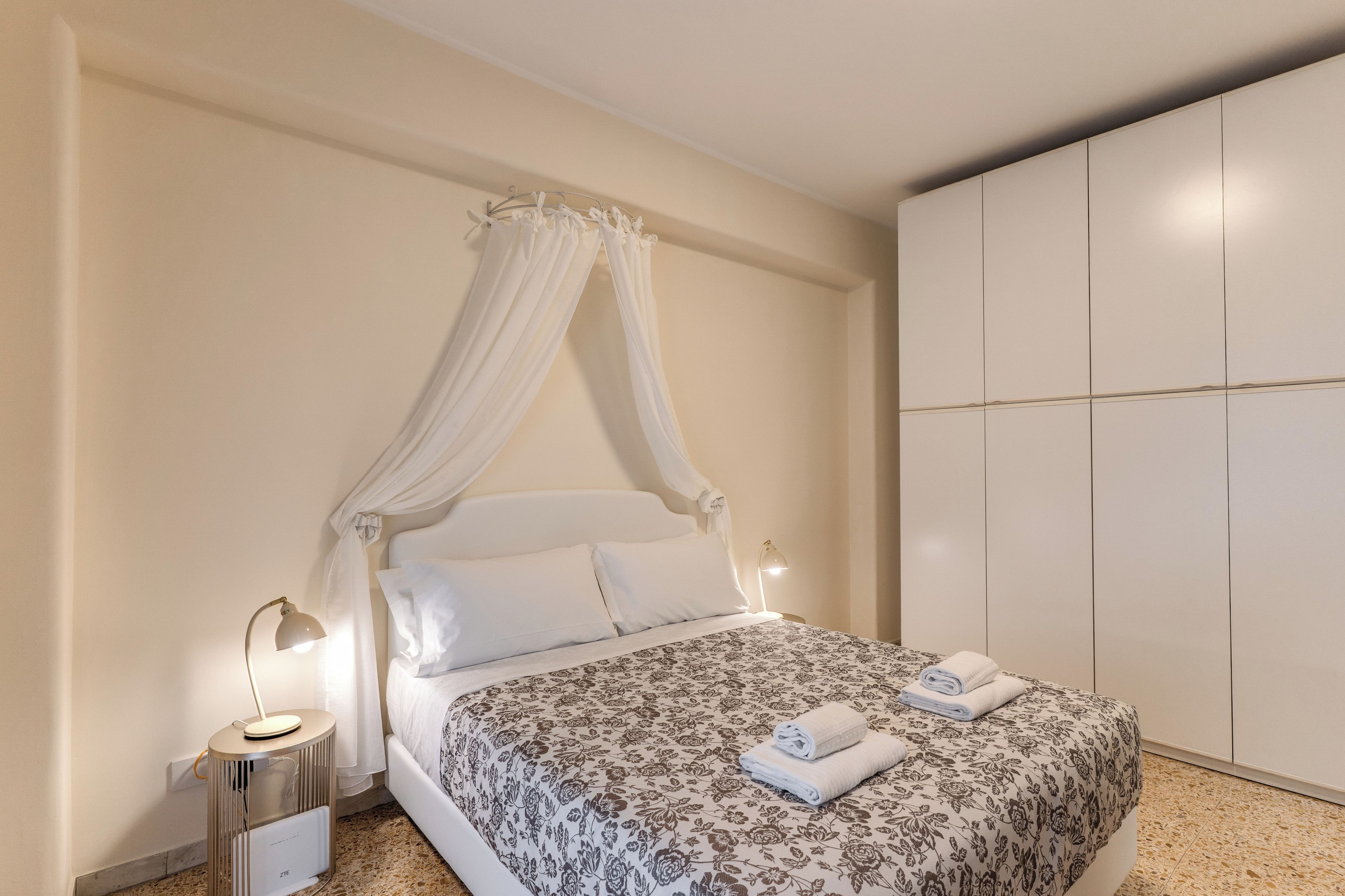 Una camera da letto con un letto a baldacchino, un comodino con una lampada e un armadio.