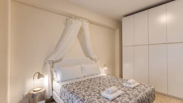 Una camera da letto con un letto a baldacchino, un comodino con una lampada e un armadio.
