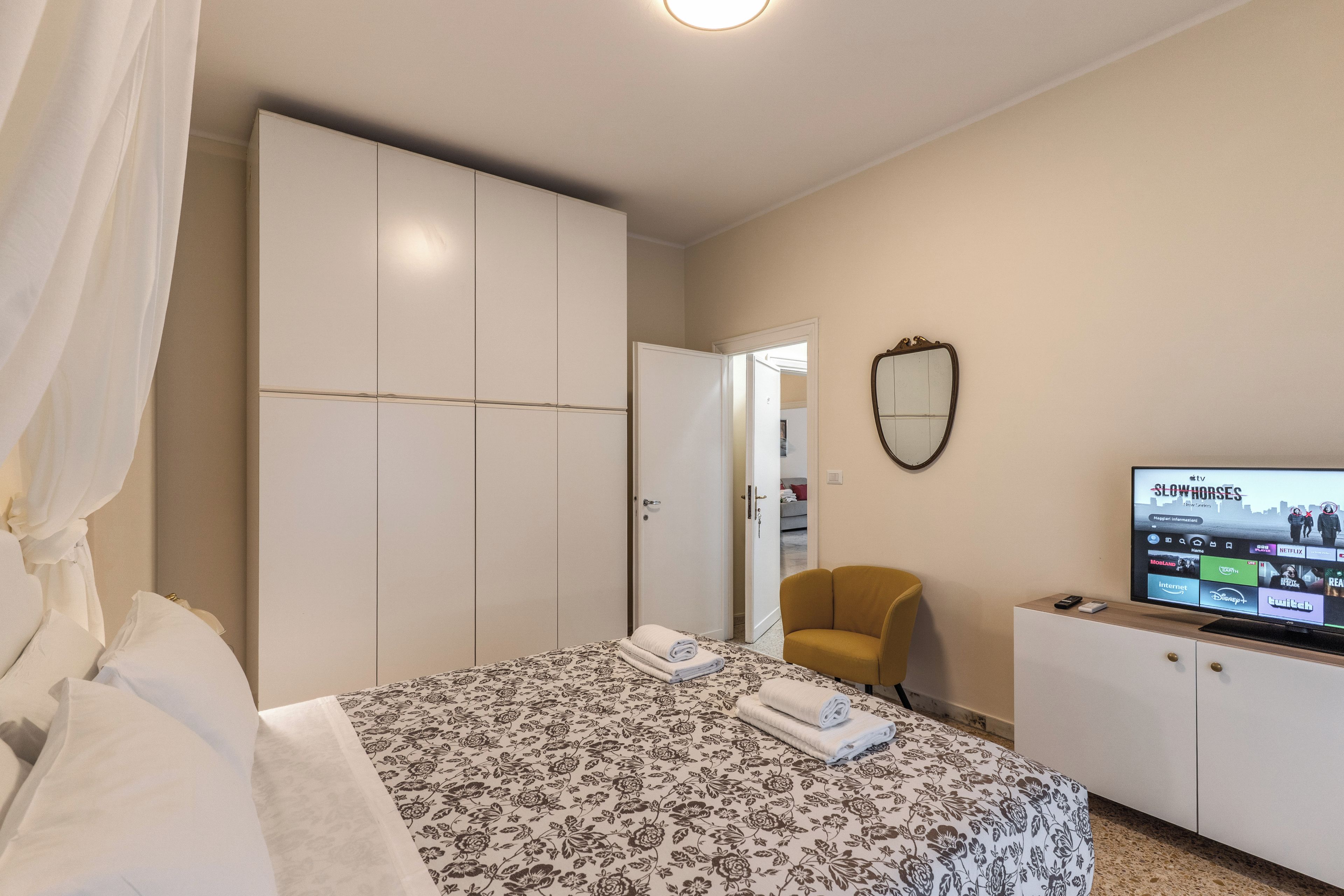 A hotel room with a bed, a wardrobe, a television, and a chair.