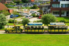 A tram with 'Ocean Wave' branding, a parking lot, and residential buildings in the background. - Inn in Leezdorf with swimming pool (Leezdorf)