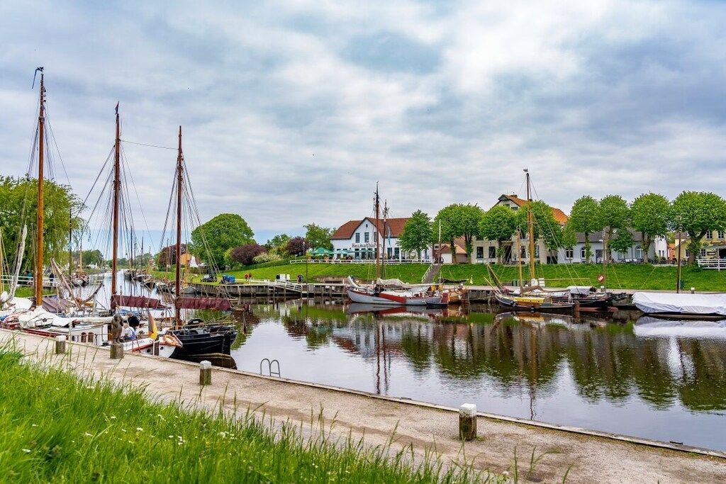 Een jachthaven met aangemeerde boten, een gazon en een gebouw op de achtergrond.