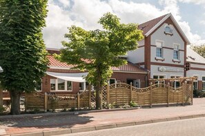 A traditional brick building with a white facade, a gated entrance, and a tree in the foreground. - Inn in Leezdorf with swimming pool (Leezdorf)