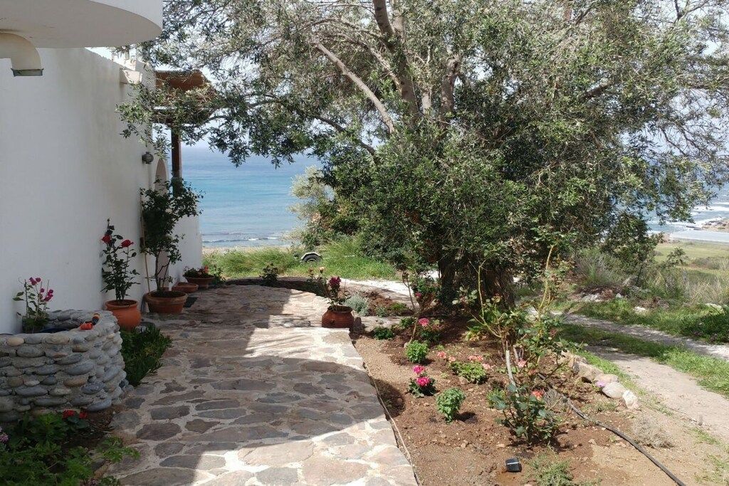 Un chemin de pierre mène à un bâtiment blanc d’où l’on a vue sur la mer.