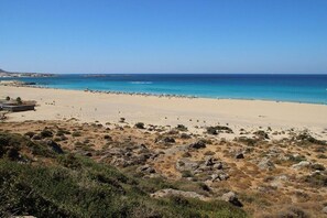 A beach with clear blue waters, sandy shore, and sparse vegetation. - Villa in Sfinari with swimming pool (Sfinari)
